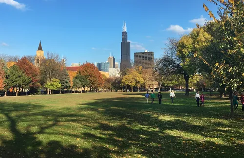 Green lawn stretches toward Chicago's skyline with Willis Tower rising in the distance