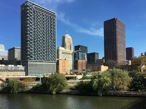 The Chicago skyline rises above the park, with willow trees lining the river