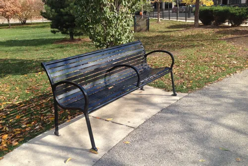Several metal benches like this one offer a place of rest along the paved pathway