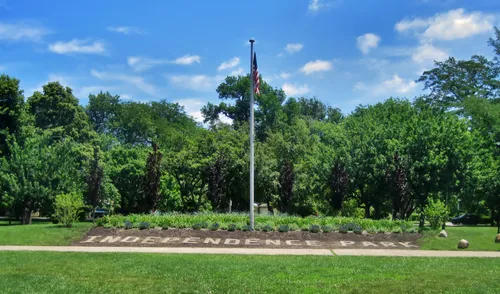 Stone lettering spells out Independence Park in front of a flagpole