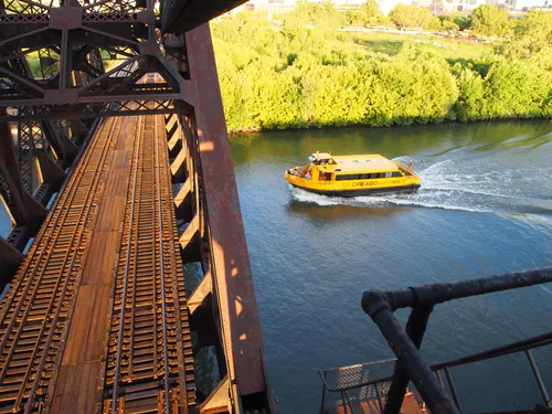 Yellow water taxi passes beneath St. Charles Air Line Bridge