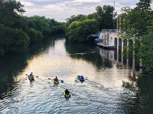 Kayakers paddle on the North Branch Chicago River alongside the park