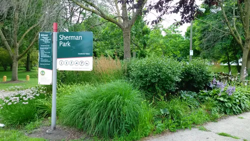 The northeast entrance to Sherman Park marked by a green sign
