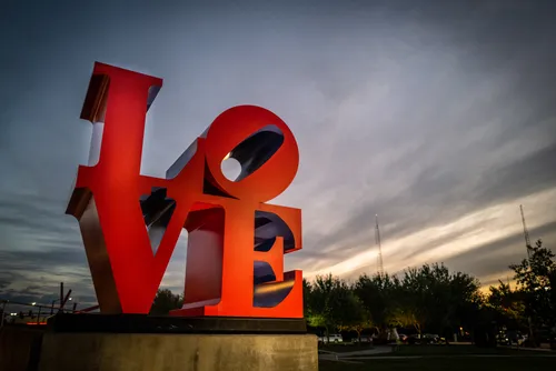 Robert Indiana's red LOVE sculpture against a dramatic night sky