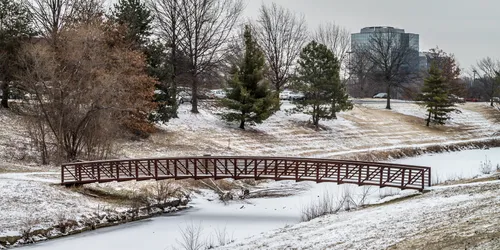 Wooden footbridge spans the frozen Summercrest Lake on a snowy winter day