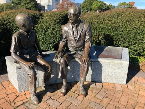 Bronze sculpture of Malcolm Woldenberg talking to a child