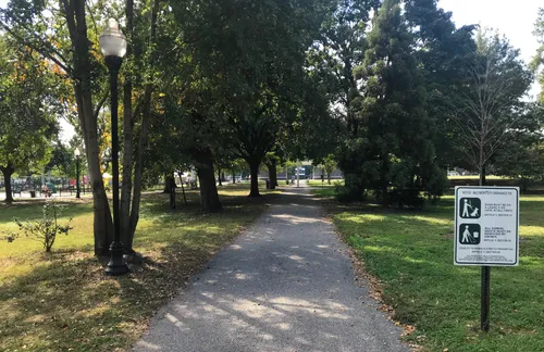 The central path leads toward the sports fields through a canopy of mature trees
