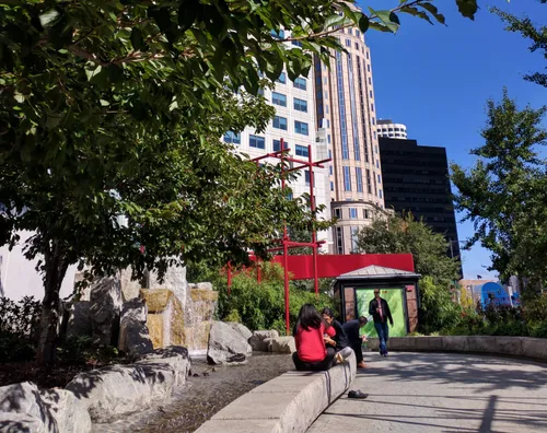 Visitors relax near the rock fountain on a sunny day
