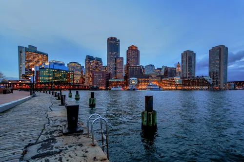 Boston's illuminated skyline at dusk viewed from the Harborwalk