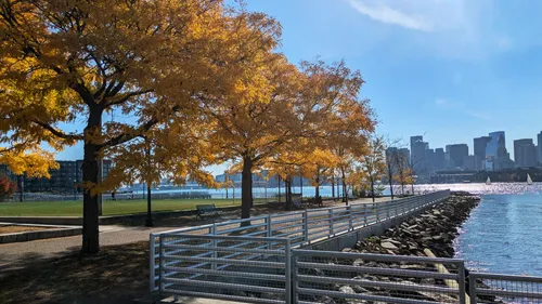 Golden autumn trees line the waterfront path with city views