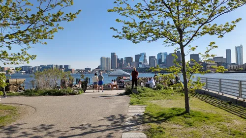 Park visitors amid spring greenery with the Boston skyline behind