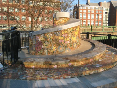 Mosaic spiral monument with brick buildings beyond
