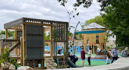 Wooden play structures and colorful surfaces at the inclusive playground area