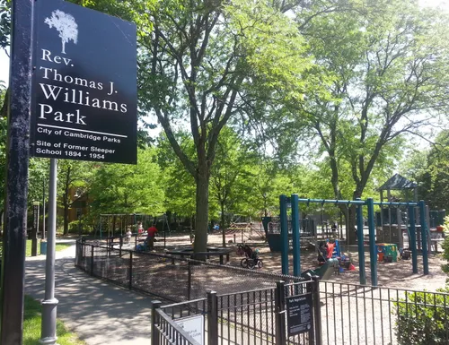 Playground equipment and shade trees visible in the park