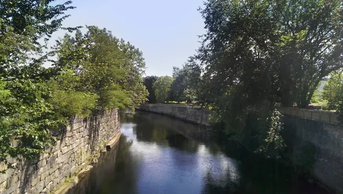 Stone walls line the calm Pawtucket Canal as it flows along the park