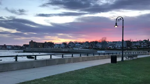 Waterfront pathway at sunset with colorful sky above