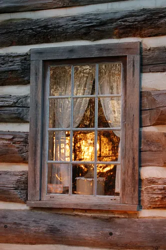 A lamp burns inside the Moon Log Cabin, visible through its rustic window