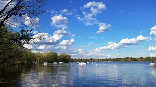 Boats dot the lake's surface under a blue sky with scattered clouds