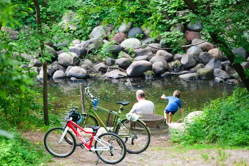 Visitors rest along the creek shore with smooth rocks lining the water