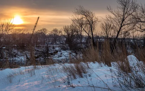 A winter sunset casts warm light over the snow-covered banks of the Mississippi River