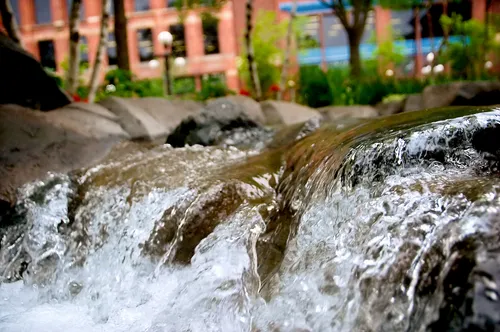 Cascading water feature with natural stone steps amid urban surroundings