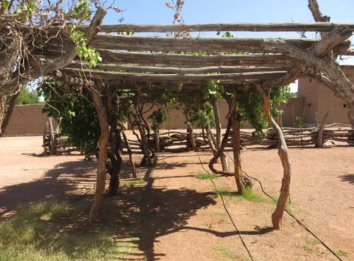 A shaded ramada structure built in the New Mexico folk carpenter style