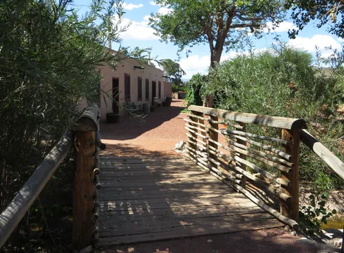 A wooden bridge crosses the narrow stream through the park