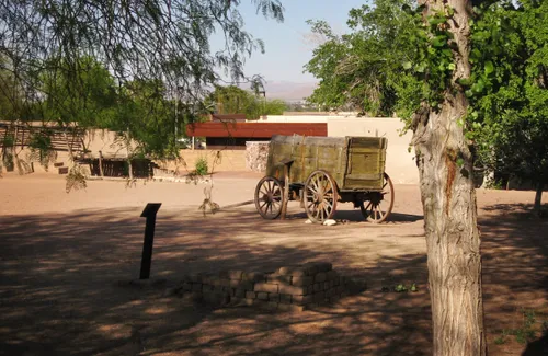 A historic wagon sits near the structures in the park's grounds