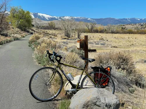 Bicycle parked along Tahoe-Pyramid Trail with snow-capped California mountains in distance
