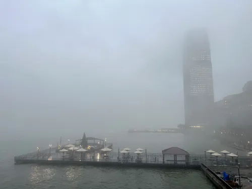 Dense fog rolls over the Hudson River, obscuring the skyline above