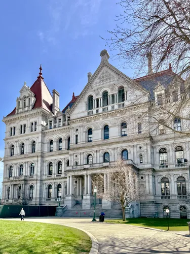 The New York State Capitol's ornate Romanesque Revival facade seen from the park