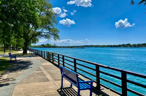 A waterfront bench along the Niagara River on a bright summer day in the park