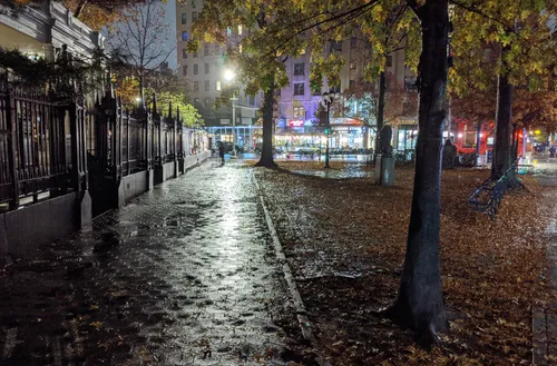 Rain-soaked leaves cover the sidewalk along the iron fence that lines the church grounds