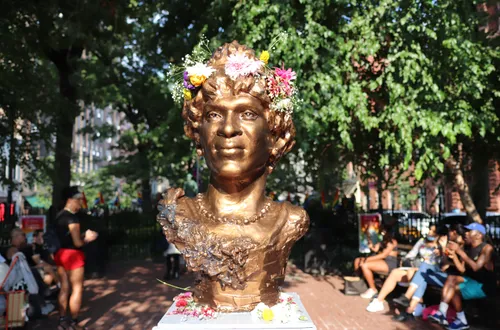 Flowers are placed on the Marsha P. Johnson bust as tributes