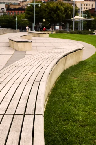 Curved wooden benches wind alongside the green lawn