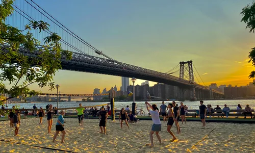 Beach volleyball near the East River with the Williamsburg Bridge at sunset