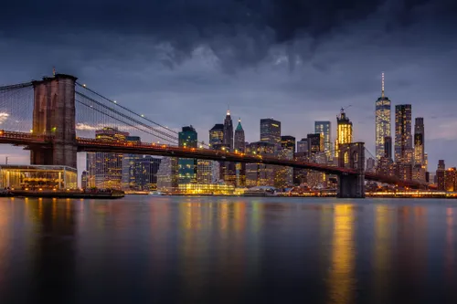 A dramatic evening view of the Brooklyn Bridge with Lower Manhattan behind it