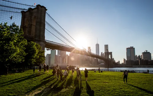 Visitors cast long shadows onto the park lawn