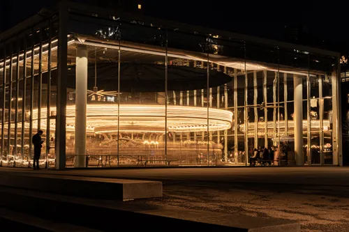 Jean Nouvel's glass pavilion housing Jane's Carousel lit up at night