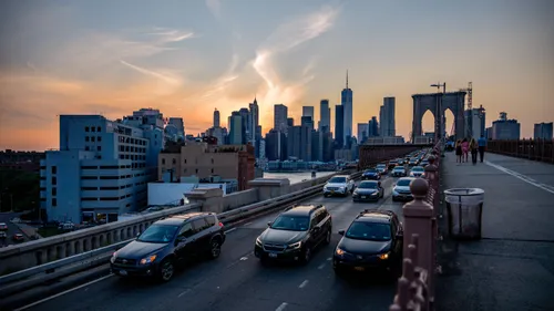 Vehicles and pedestrians cross the Brooklyn Bridge at sunset