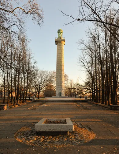 The tall Prison Ship Martyrs Monument stands at the end of a tree-lined path