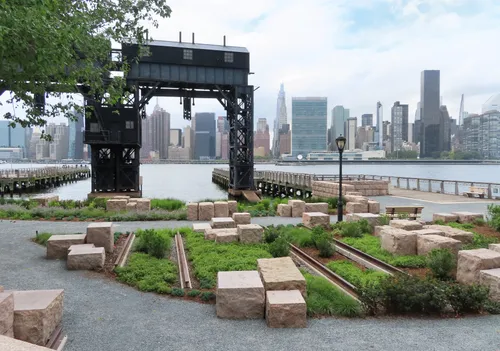 Historic gantry structures at the docks frame a view of the Manhattan skyline