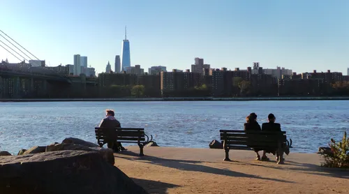 Visitors on benches enjoying views of Manhattan across East River