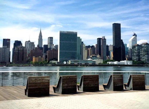 Waterfront seating along the promenade with the Midtown Manhattan skyline across the East River