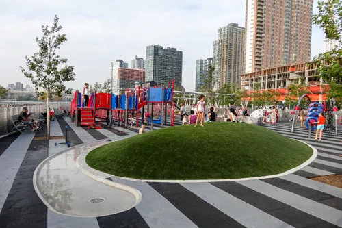 Kids explore the oval grass mound in the playground area