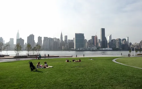 Open lawn space along the waterfront with the Manhattan skyline stretching across the horizon