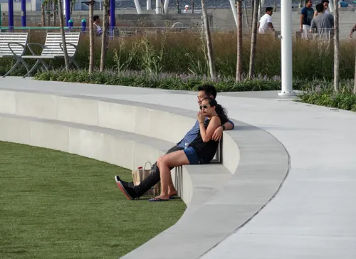 A couple relaxes along the seating wall in the park's central green area
