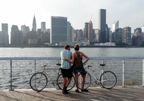 Two visitors with bikes take in the Manhattan skyline from the East River waterfront