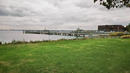 Grassy waterfront area with a pier extending into the harbor