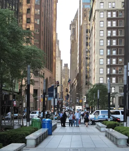 A wide walkway through the park looks out along Wall Street